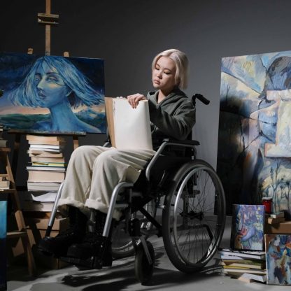 girl on wheel chair doing painting